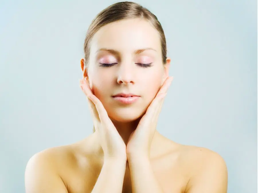 Picture of a woman massaging her face with essential oils